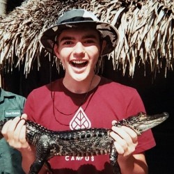 An AVC student holds a baby crocodile during a field trip.